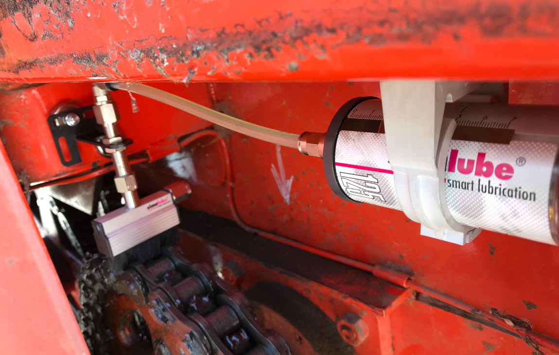 The chain of an agricultural harvesting vehicle is automatically lubricated with a simalube lubricator and also cleaned at the same time thanks to the applied brush.