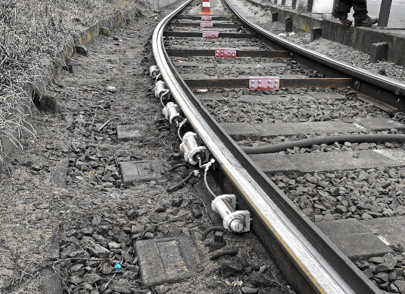 Several 250 ml lubricators are installed with a retaining clip and hose connection in the curve of a railway track. The continuous lubricating film prevents the squeaking of the rail in the curves.